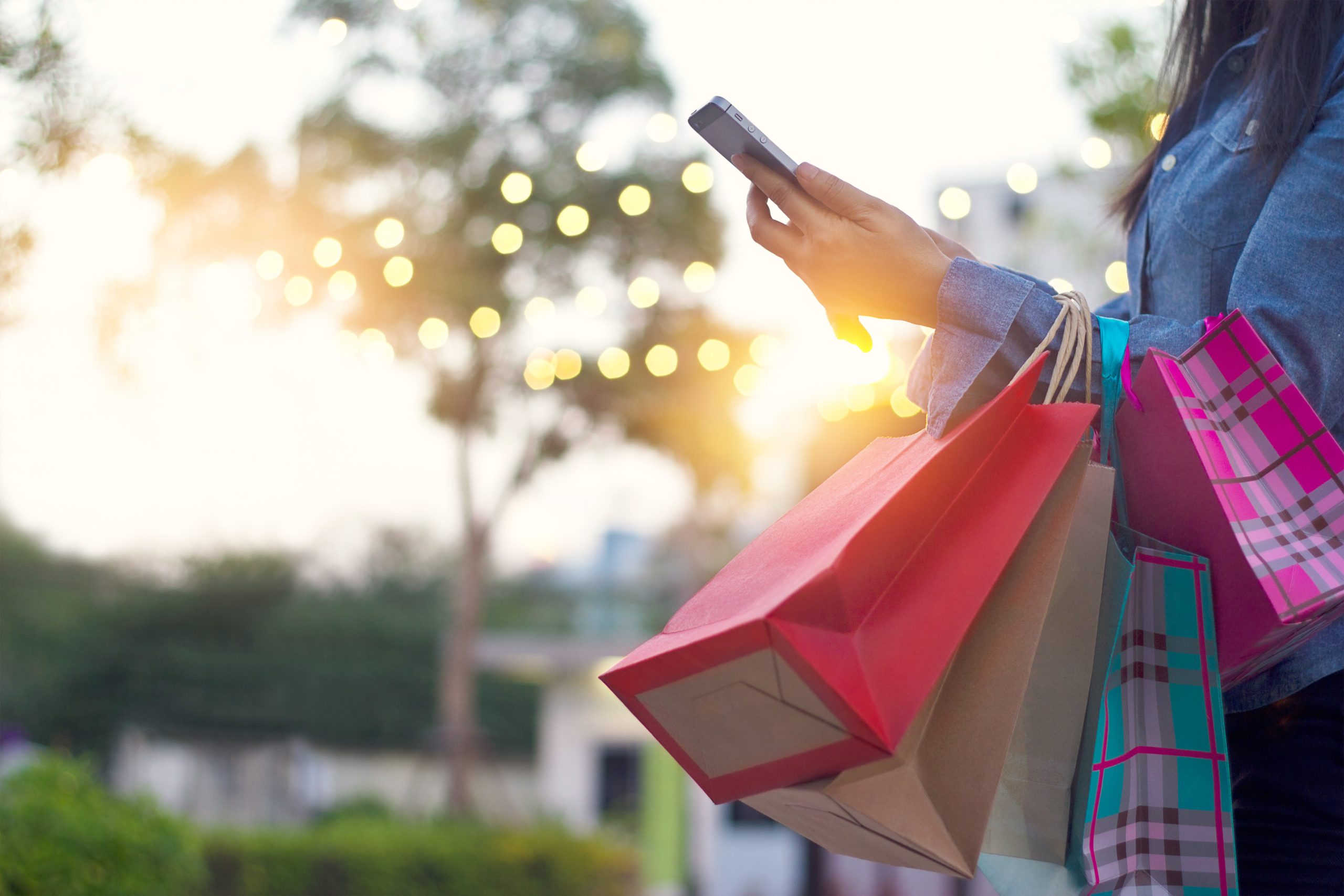 Woman using smartphone with shopping bag in hands